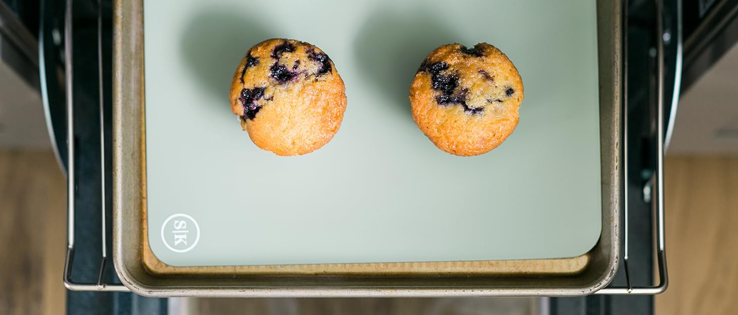 Blueberry muffins baked in silicone baking cups on a baking sheet with a silicone baking mat