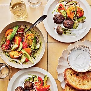 photo of bowl filled with tomato salad next to plates holding salad and meatballs