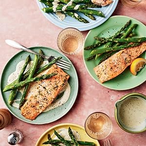 green plates holding salmon and asparagus on a pale pink tablecloth