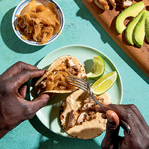 person serving themselves Papa's Famous Chicken Yassa Tacos