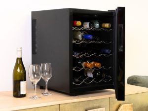 Black wine fridge set up on an elegant gold sideboard with a wine bottle and two glasses