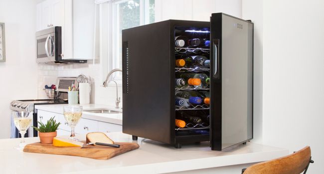 20-bottle thermoelectric wine cooler on a white counter with white wine and cheese tray beside it