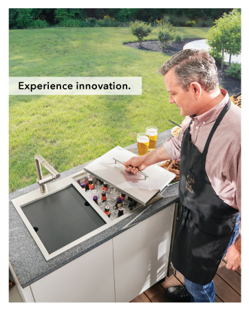 Man wearing bbq apron stands at Ruvati outdoor sink and cooler.