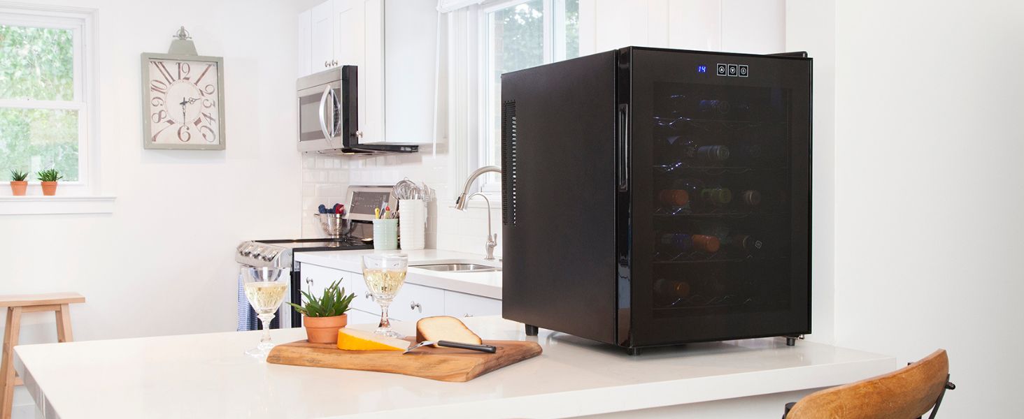 20-bottle thermoelectric wine cooler on a white counter with white wine and cheese tray beside it