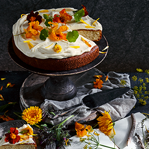 A photo of Yasha' Flower Cake on a cake stand with flowers
