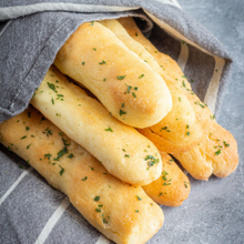 6 breadsticks in pyramid formation, garnished with parsley and partially wrapped in a towel