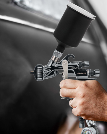 person holding spray gun car door in background