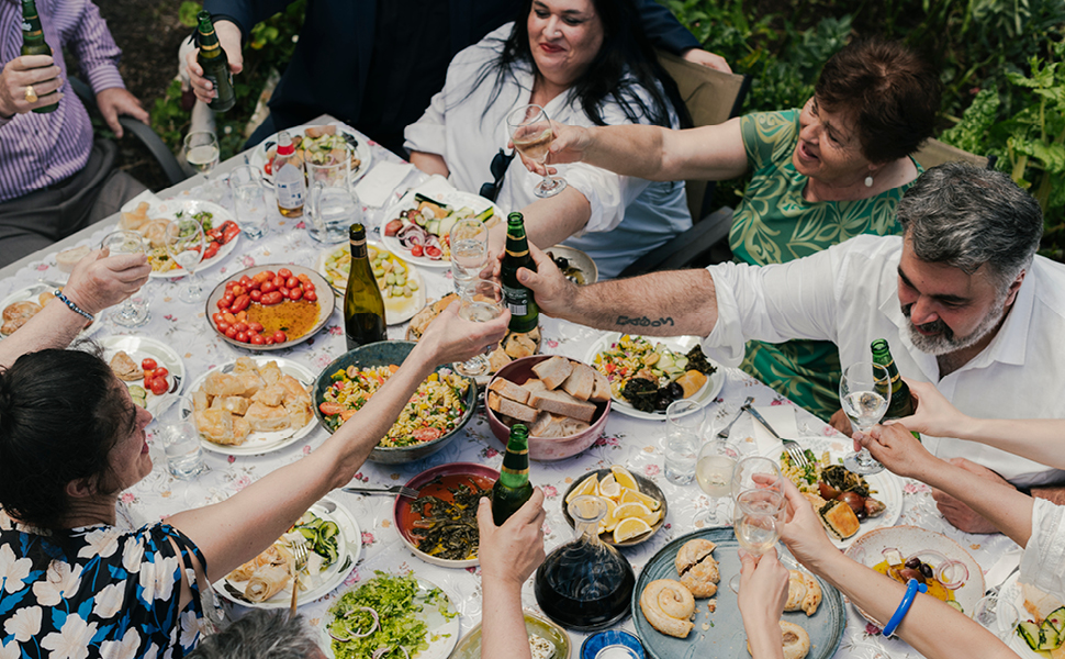 A group of friends and family sit around a beautiful spread of food and wine