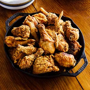 Several pieces of fried chicken arranged in a black cast iron pan.