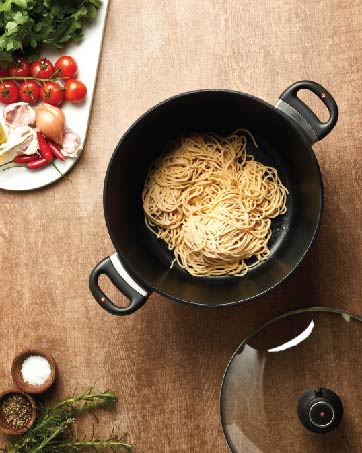 pasta in a pot with lid, with various foods and herbs laid around the pot 