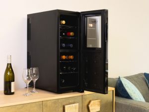 Black compact wine fridge set up on an elegant gold sideboard with a bottle and wine glasses beside