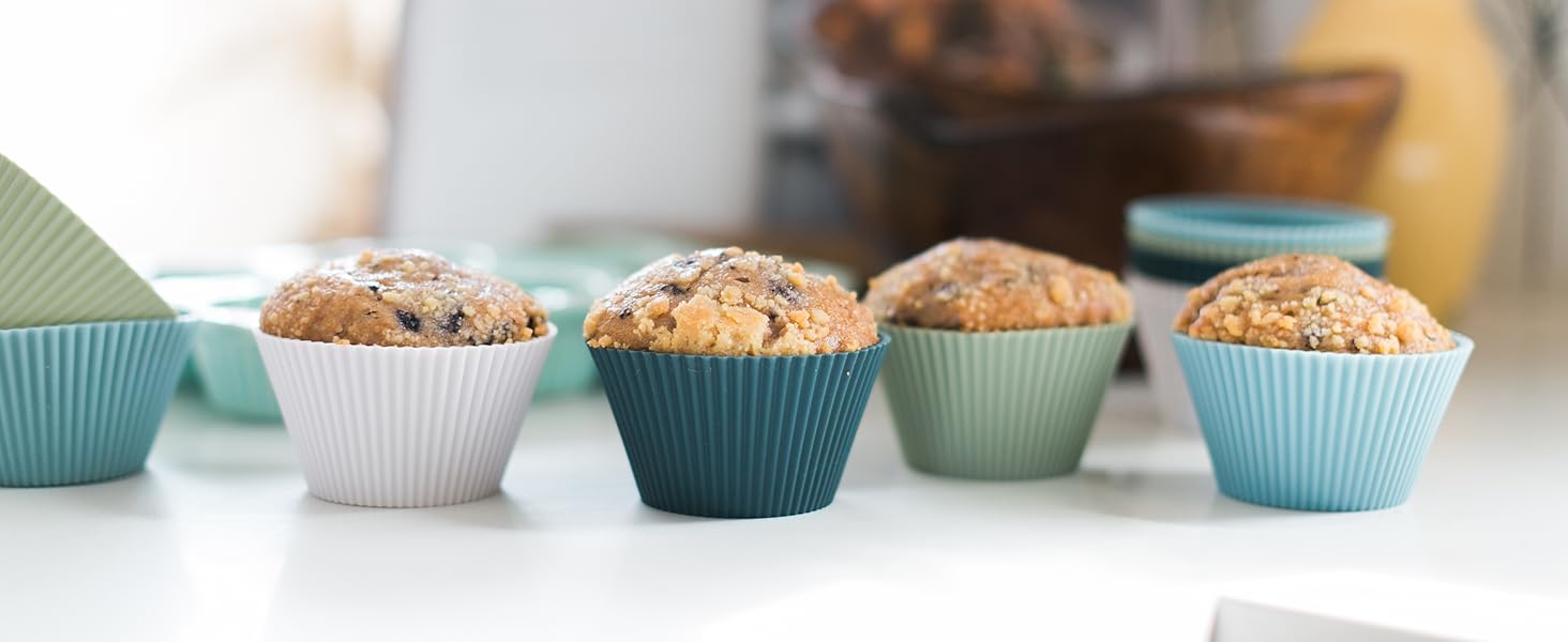 Free-standing silicone baking cups in white, navy, sage, and light blue with muffins in them