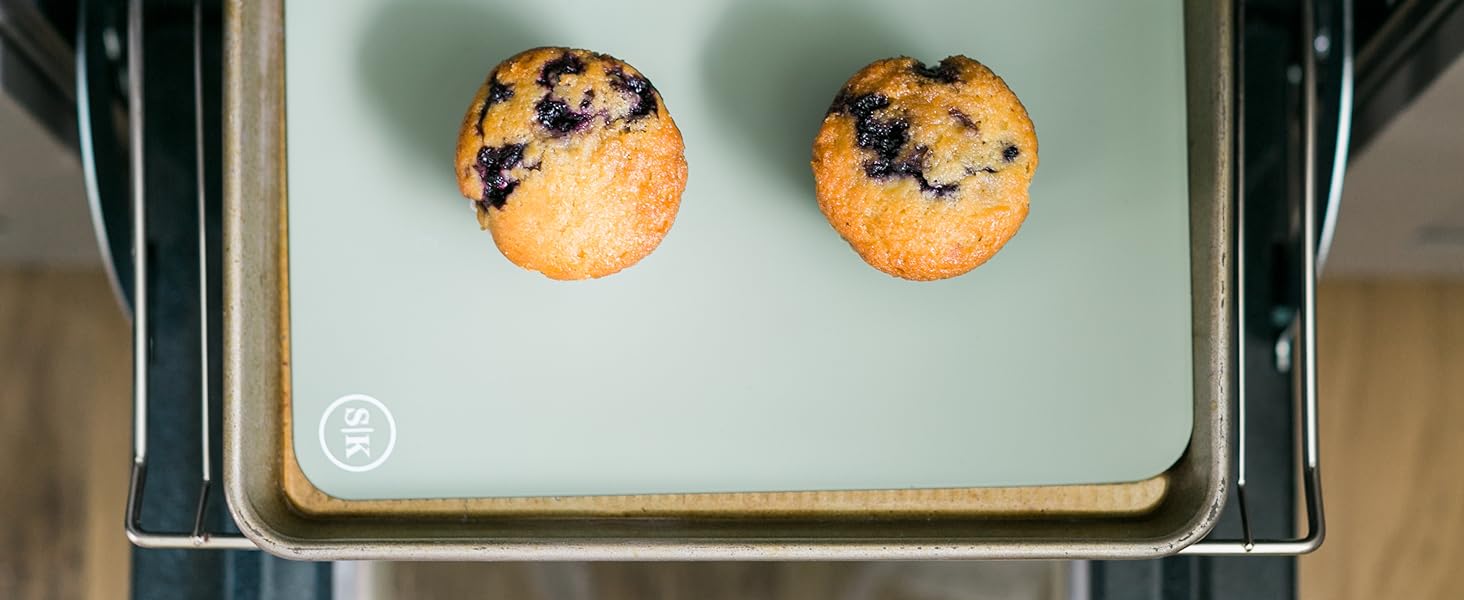 Blueberry muffins baked in silicone baking cups on a baking sheet with a silicone baking mat