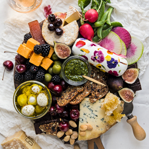 A photo of a cheese board with cheese crackers and fruit on a table. 