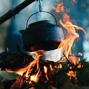 A steel kettle hanging over a small fire. 